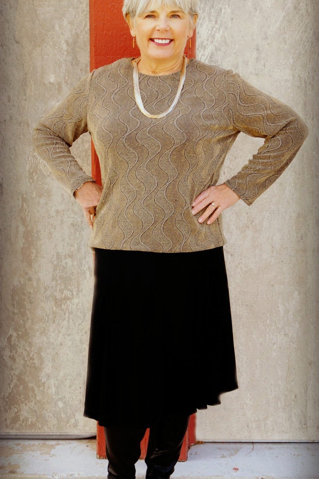 Textured beige knit sweater over black midi skirt with pearl necklace, classic winter outfit for women over 60