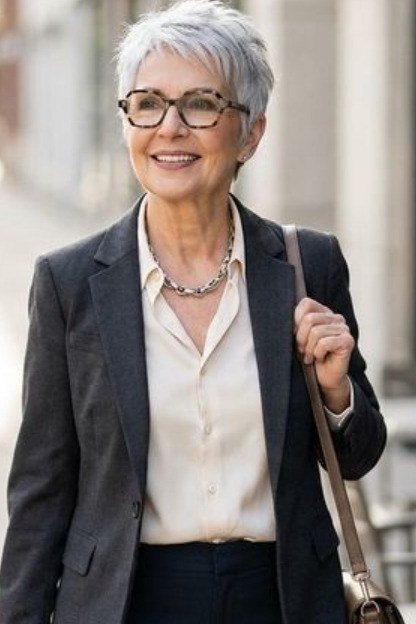 Smiling older woman in gray blazer and white shirt on a cafe terrace