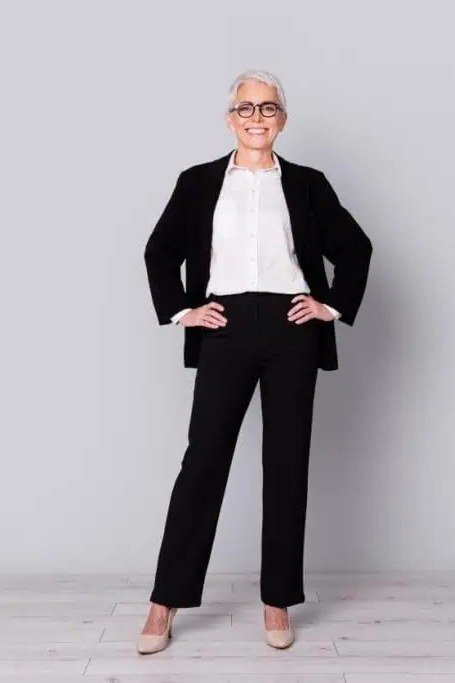 Woman in black blazer, white top and black trousers in a white studio