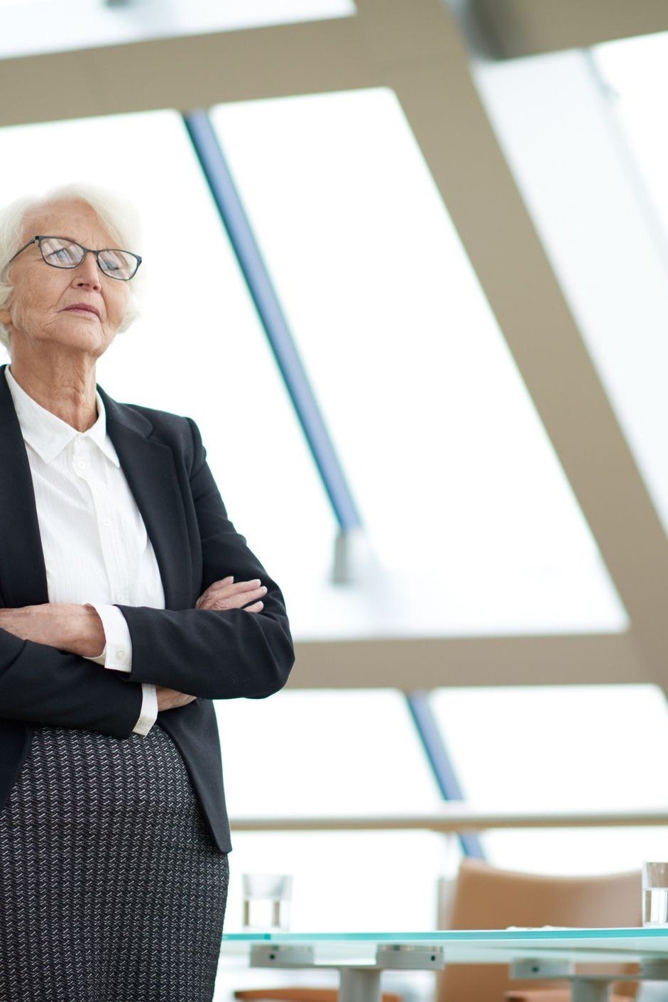 Woman in black blazer, white shirt and gray pencil skirt in a modern office