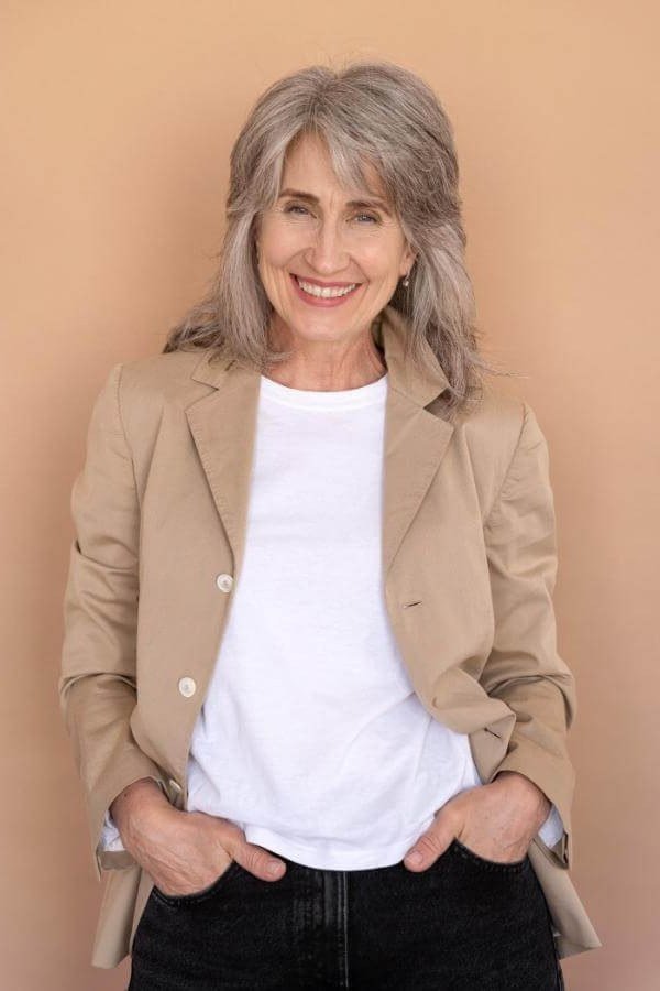Smiling woman in tan blazer, white tee and black jeans