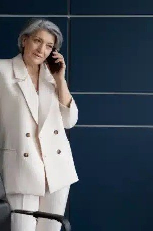 Woman in cream double-breasted blazer talking on the phone in an office