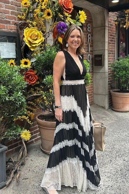 Woman over 50 wearing a black and white tie-dye wrap-look maxi dress with sash at a flower shop