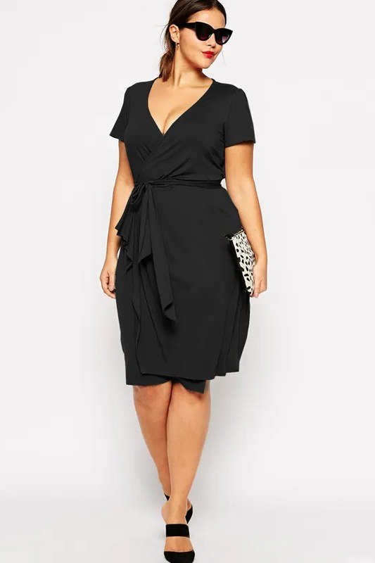 Plus-size woman over 60 in a black wrap midi dress with sunglasses in a studio