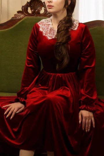 red velvet midi dress with lace collar seated on green sofa