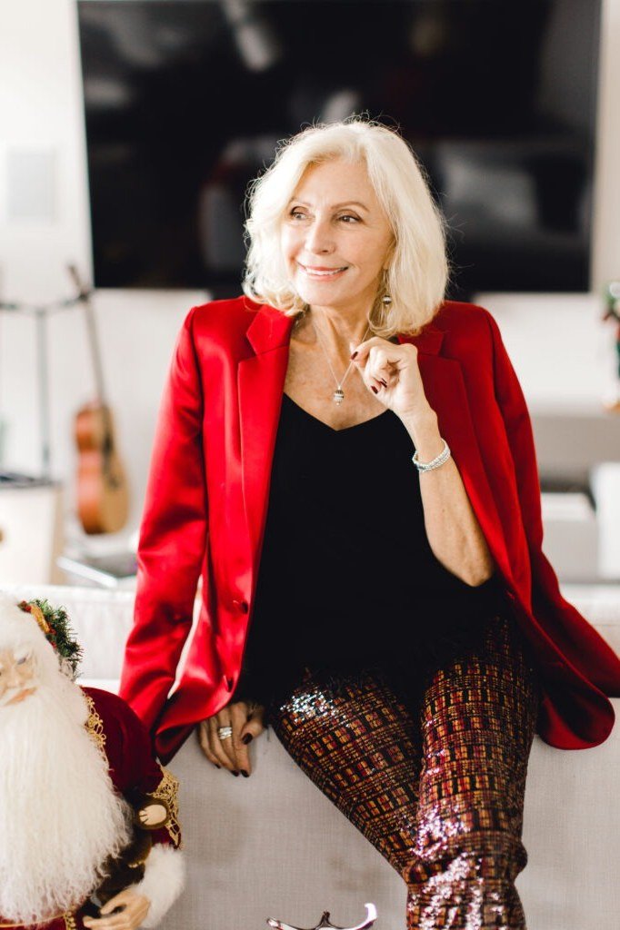 Red Velvet Blazer with Sequin Pants worn by older woman, red velvet blazer with black top and sequin pants seated