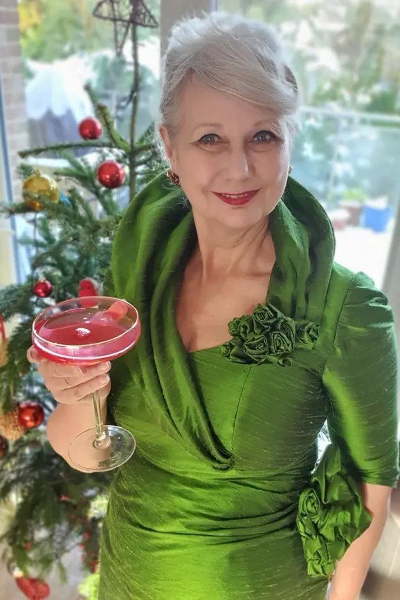 green dupioni silk dress holding cocktail by christmas tree
