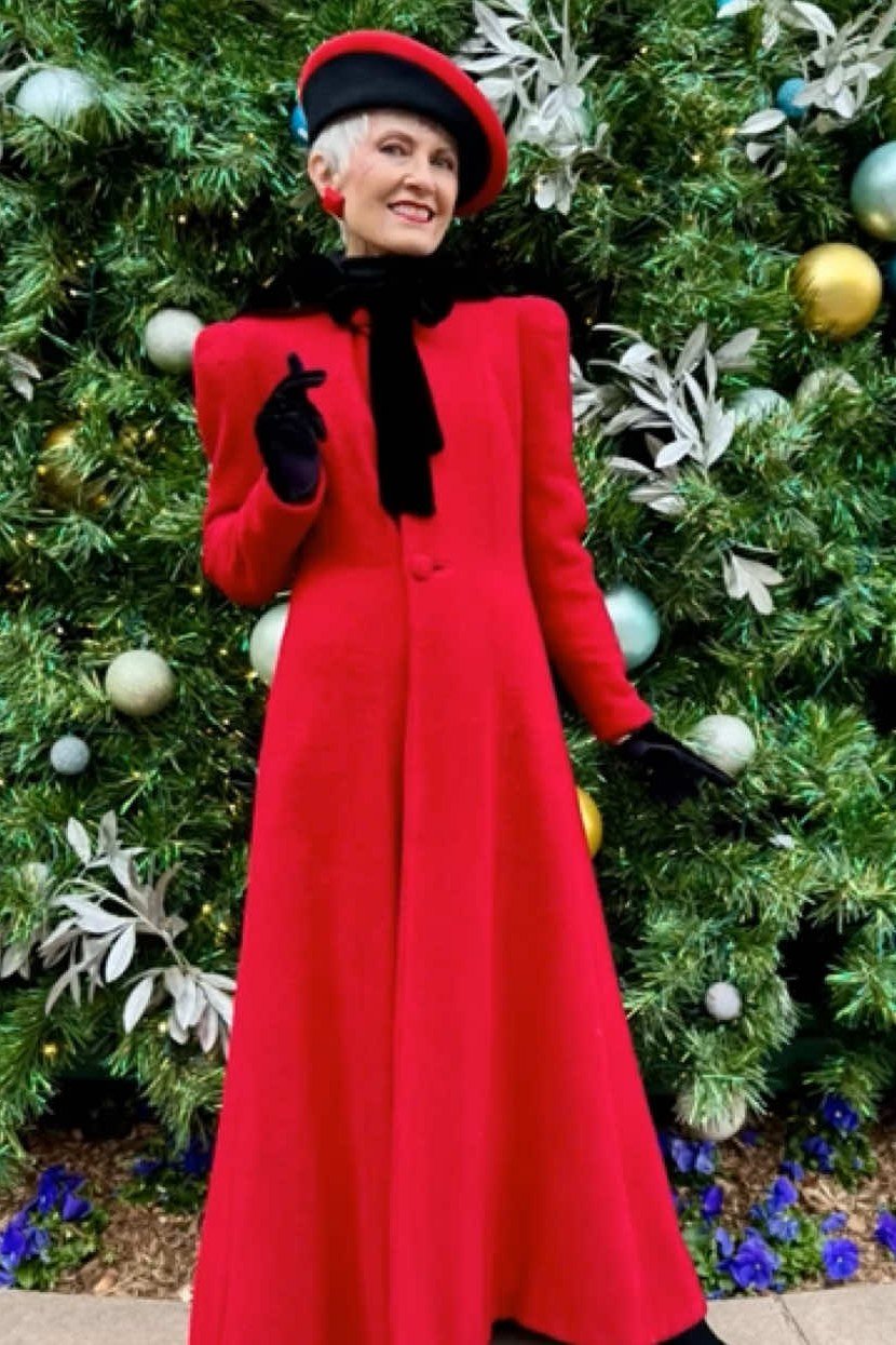 long red coat with red beret standing by christmas tree