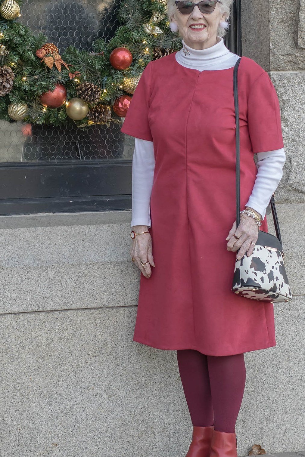 Red Dress Layered Over a White Turtleneck worn by older woman, red short-sleeve dress over white turtleneck with brown boots