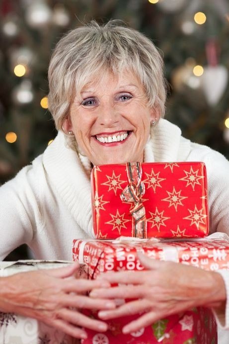 White Knit Sweater with Wrapped Gifts worn by older woman, white knit sweater holding wrapped gifts by tree