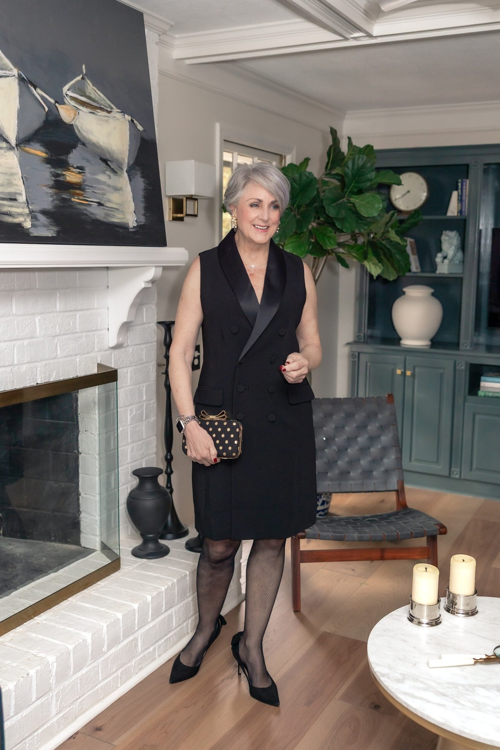 Black Sleeveless Cocktail Dress by the Fireplace worn by older woman, black sleeveless cocktail dress by white fireplace