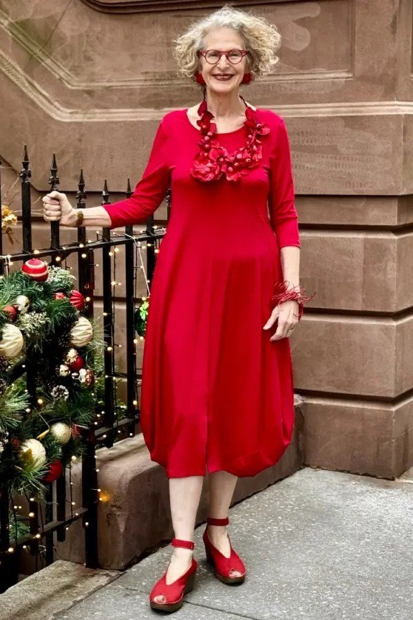 Red Midi Dress with a Red Statement Necklace worn by older woman, red midi dress with red statement necklace on city street
