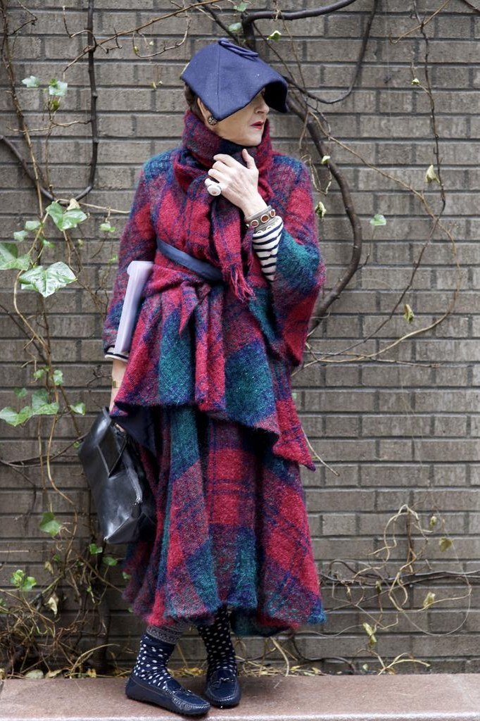 red blue tartan wrap with hat by brick wall