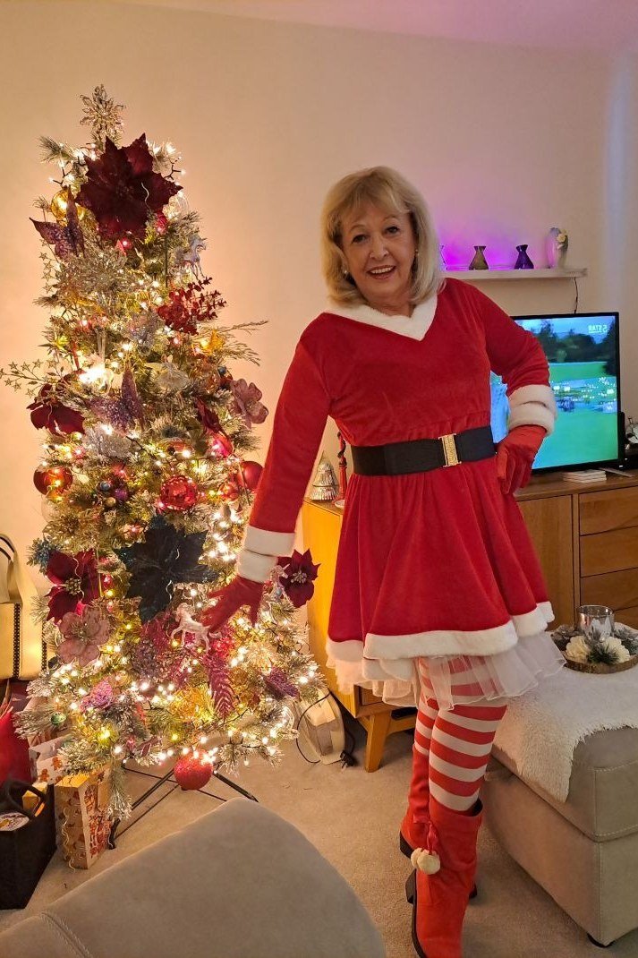 Mrs. Claus Red Dress with a Black Belt worn by older woman, mrs Claus red dress with black belt by Christmas tree
