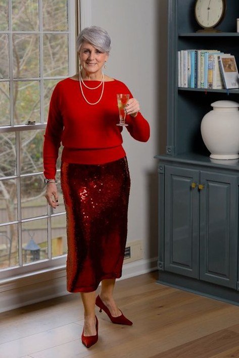 red top with red sequin midi skirt holding champagne glass